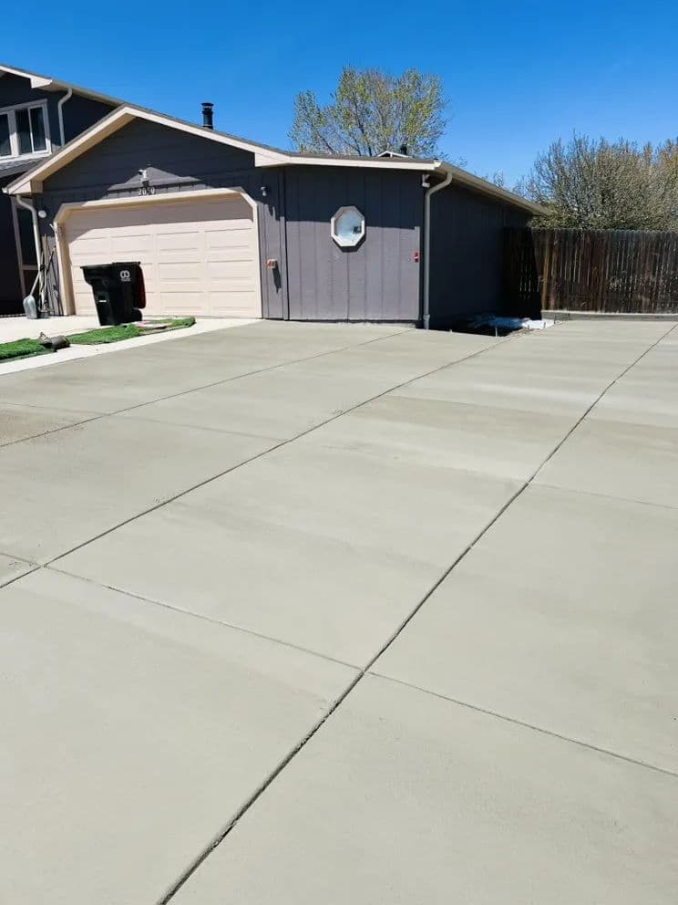 Newly poured concrete driveway and garage, clear blue sky in the background.