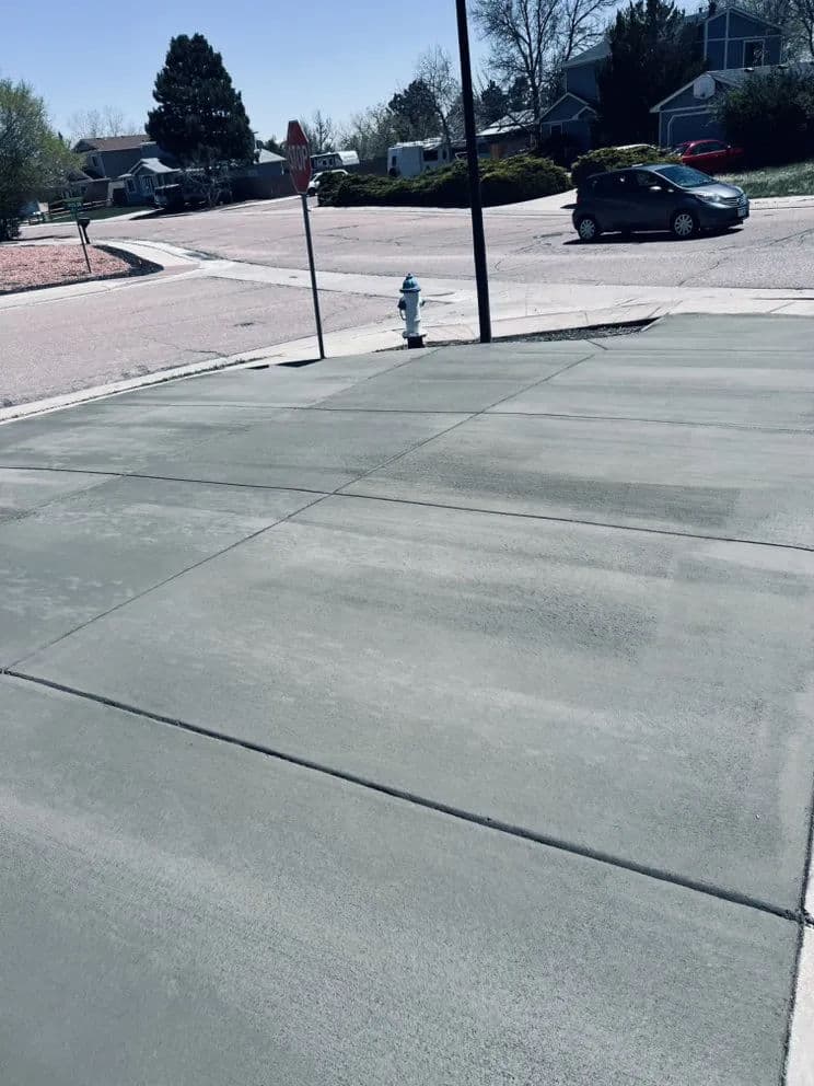 Freshly poured concrete driveway near a stop sign and fire hydrant in a residential area.