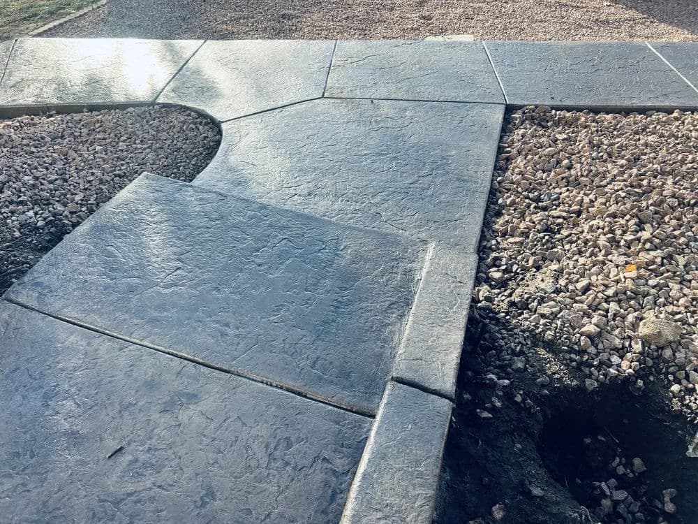 Decorative concrete sidewalk with textured finish and gravel landscaping details.