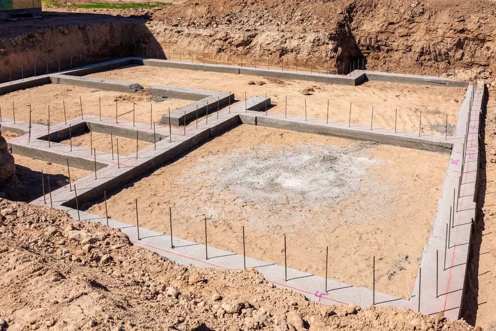 Construction site foundation with concrete blocks and steel rebar for a new building.