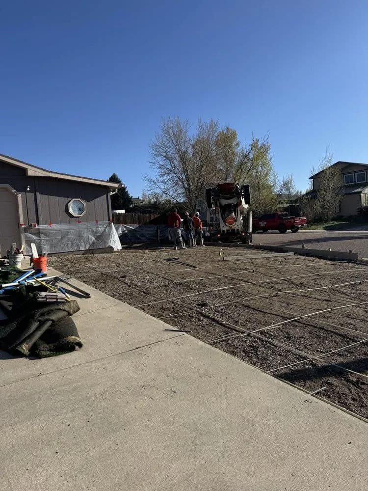 Construction site with workers, cement truck, and prepared ground for pouring concrete.