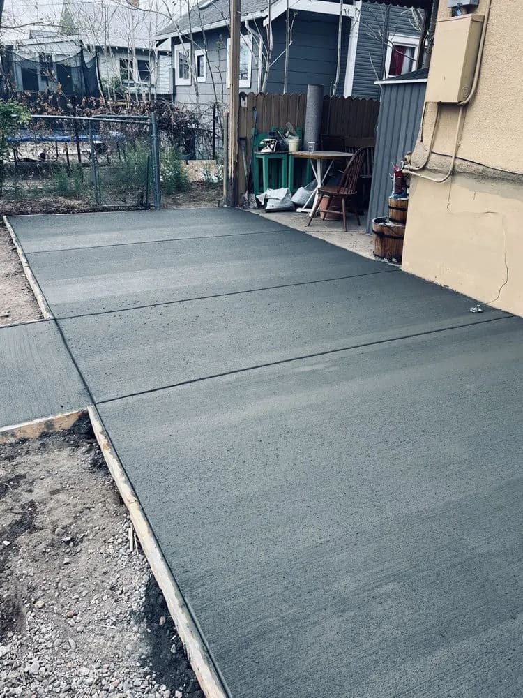 Freshly poured concrete patio ready for outdoor use in a residential backyard.