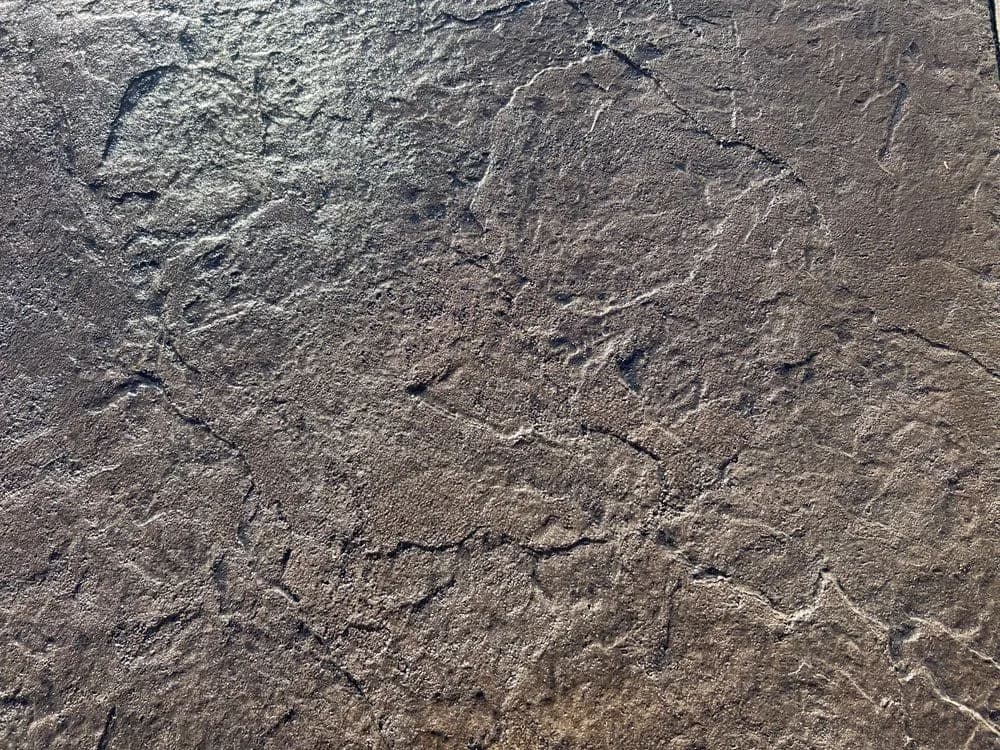 Textured surface of natural stone with cracks and patterns, perfect for design inspiration.
